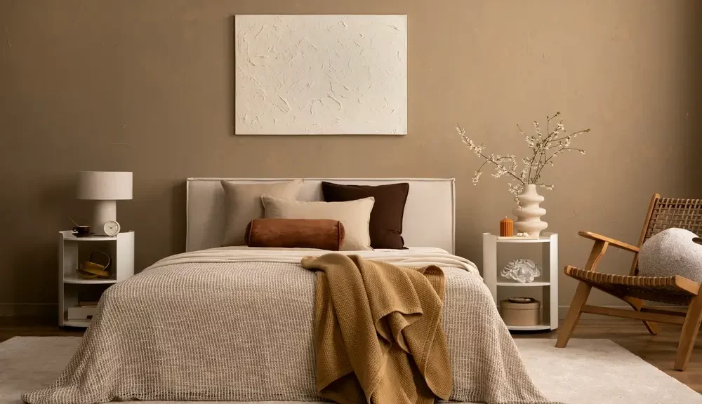 L'intérieur minimaliste de la chambre à coucher comprend une literie neutre, des touches de brun chaud et des tables de chevet stylisées sur un mur beige à texture.