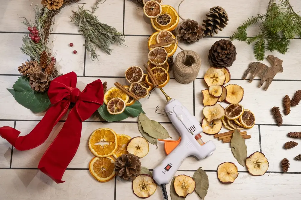 Bricolage rustique Noël Wreath Craft avec pistolet à colle, fruits secs, et Pinecones Flat Lay.
