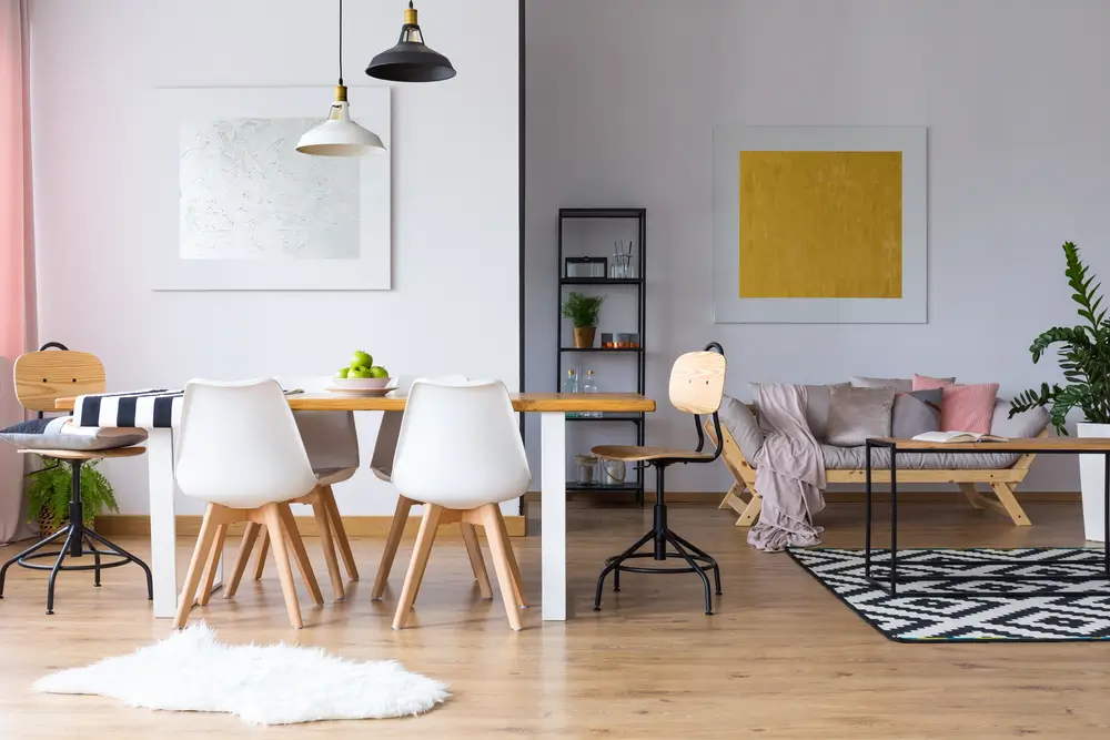 Fourrure sur le parquet près de la table à manger avec des chaises blanches dans une pièce spacieuse avec canapé et galerie.